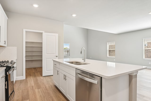 kitchen featuring light countertops, stainless steel dishwasher, black range with gas stovetop, a sink, and light wood-type flooring