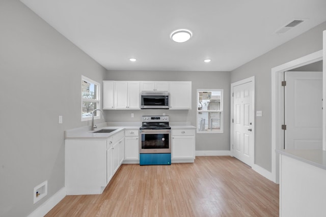 kitchen featuring light wood finished floors, visible vents, light countertops, stainless steel appliances, and a sink