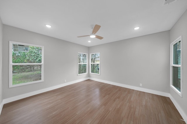 empty room with wood finished floors, a healthy amount of sunlight, and baseboards