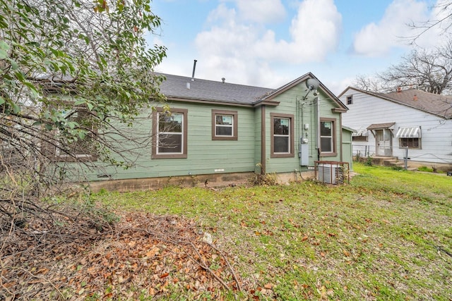 rear view of house featuring central air condition unit, a lawn, and fence