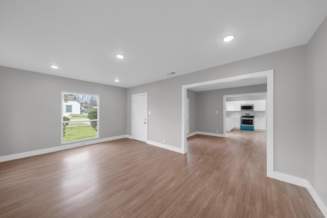 empty room featuring recessed lighting, baseboards, and light wood finished floors