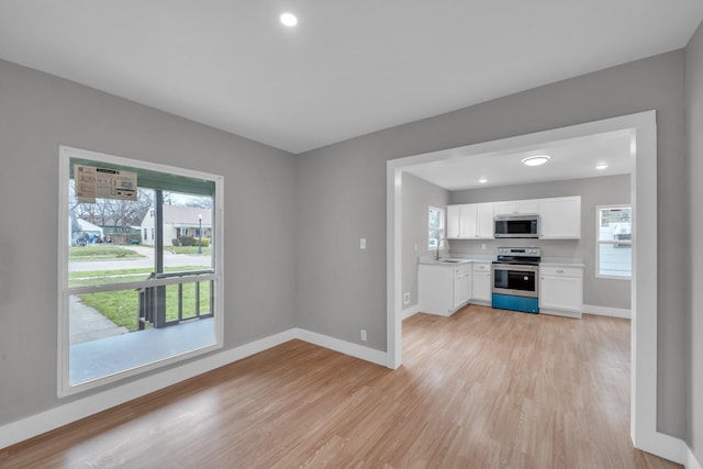 kitchen featuring a sink, light wood-type flooring, white cabinetry, and stainless steel appliances