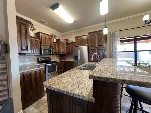 kitchen with a breakfast bar, a sink, ornamental molding, appliances with stainless steel finishes, and decorative backsplash