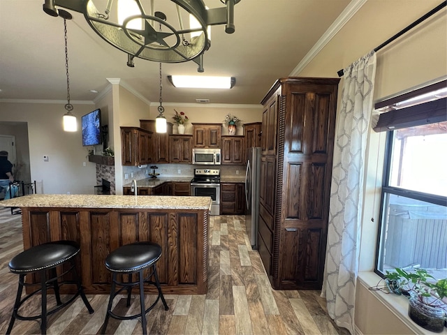 kitchen featuring dark brown cabinetry, decorative backsplash, appliances with stainless steel finishes, a kitchen breakfast bar, and ornamental molding