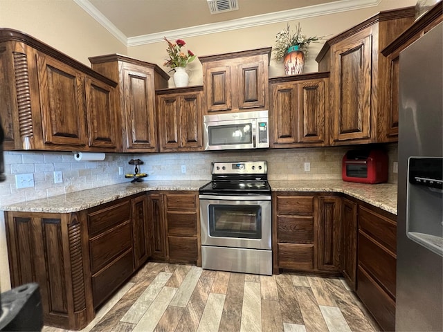 kitchen with visible vents, ornamental molding, appliances with stainless steel finishes, backsplash, and light stone countertops