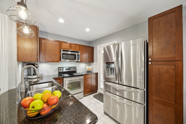 kitchen with appliances with stainless steel finishes, dark stone countertops, a sink, and tasteful backsplash