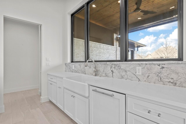 interior space featuring a wealth of natural light, white cabinets, a sink, and light countertops