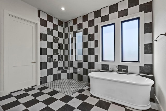 full bath with a freestanding tub, a shower stall, tile walls, and tile patterned floors