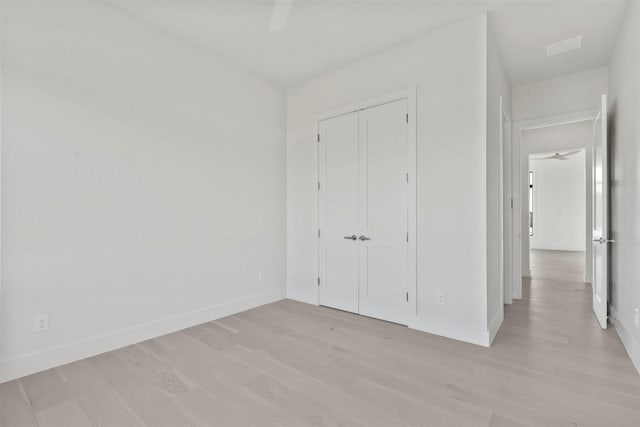 unfurnished bedroom with a closet, visible vents, ceiling fan, light wood-type flooring, and baseboards