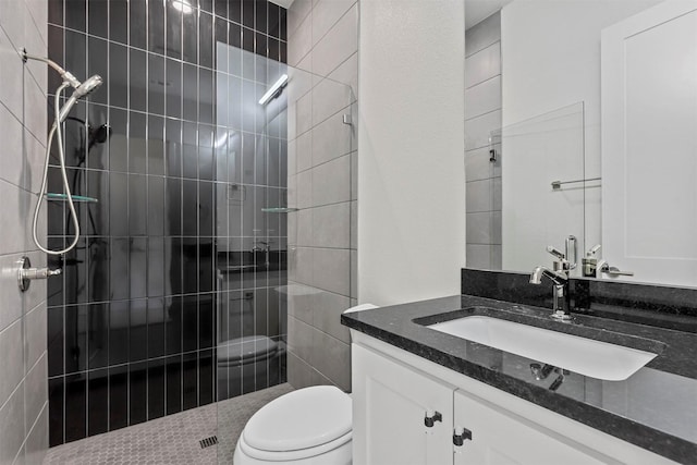 bathroom featuring toilet, tiled shower, and vanity