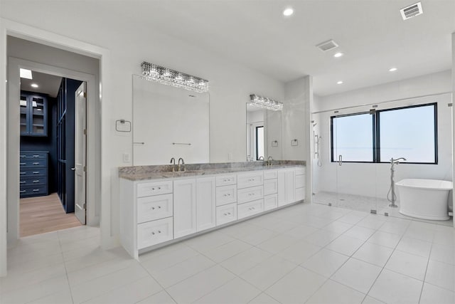 bathroom with a stall shower, visible vents, a sink, and tile patterned floors