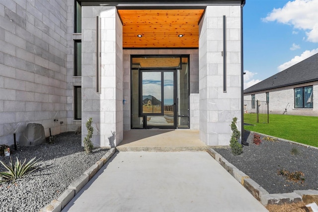 view of exterior entry featuring concrete block siding and a yard