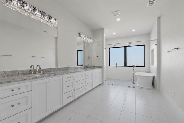 bathroom featuring double vanity, a soaking tub, a sink, and visible vents