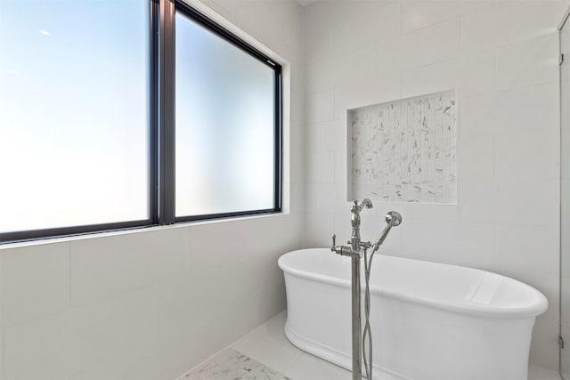 full bath with a freestanding tub and tile walls