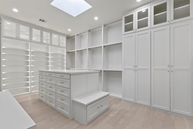 walk in closet featuring light wood-style floors, a skylight, and visible vents