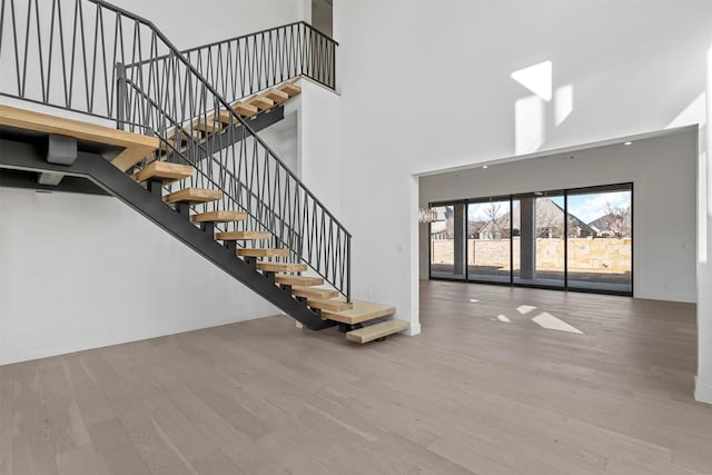 interior space with stairway, a high ceiling, baseboards, and wood finished floors