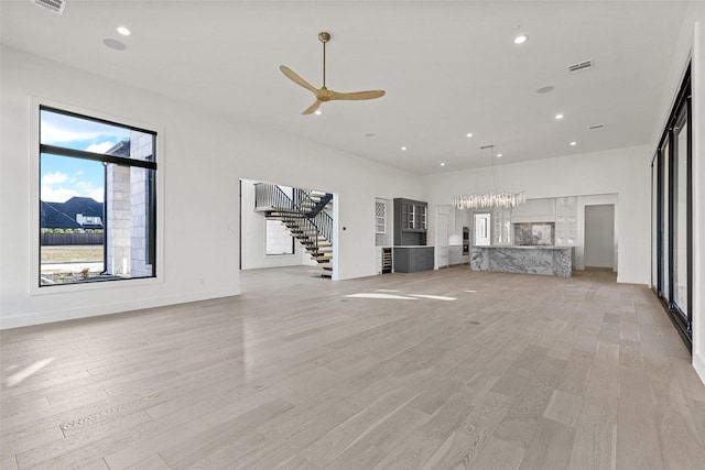 unfurnished living room with ceiling fan, light wood-style flooring, recessed lighting, visible vents, and stairway