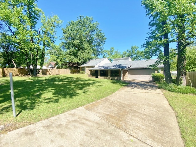 view of front of house featuring a garage, a front yard, concrete driveway, and fence