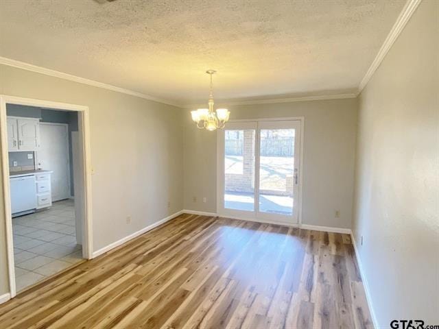 unfurnished room with a textured ceiling, light wood-style floors, an inviting chandelier, baseboards, and ornamental molding