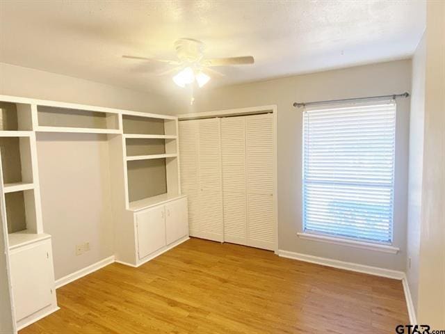 unfurnished bedroom with ceiling fan, baseboards, light wood finished floors, and a closet