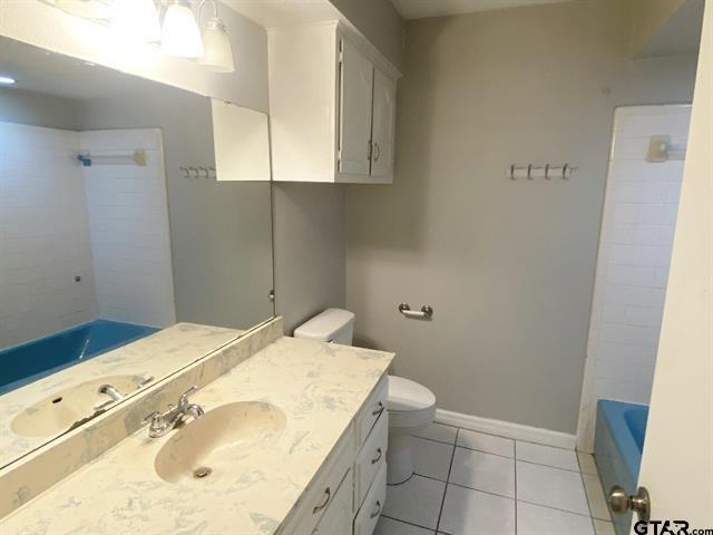 full bath with tile patterned floors, toilet, vanity, baseboards, and  shower combination