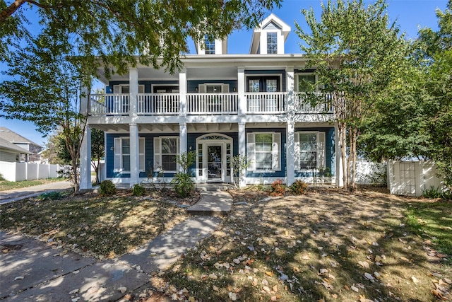 view of front of home featuring covered porch, fence, and a balcony