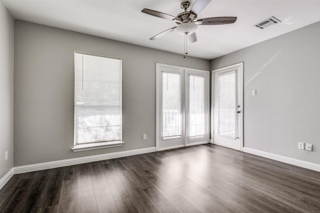 spare room featuring dark wood-style flooring, visible vents, ceiling fan, and baseboards