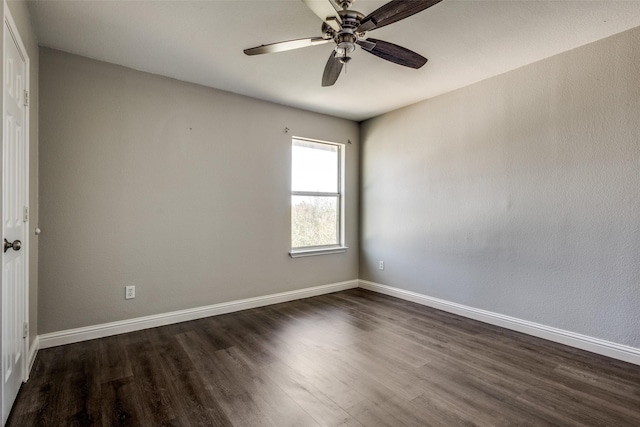 spare room with dark wood-style flooring, a ceiling fan, and baseboards