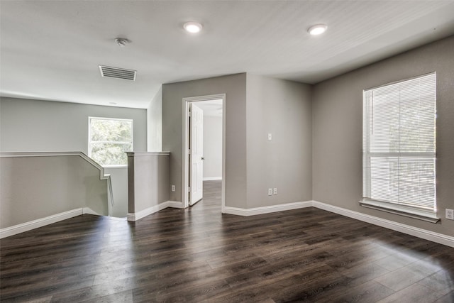 spare room featuring baseboards, visible vents, and dark wood-style flooring