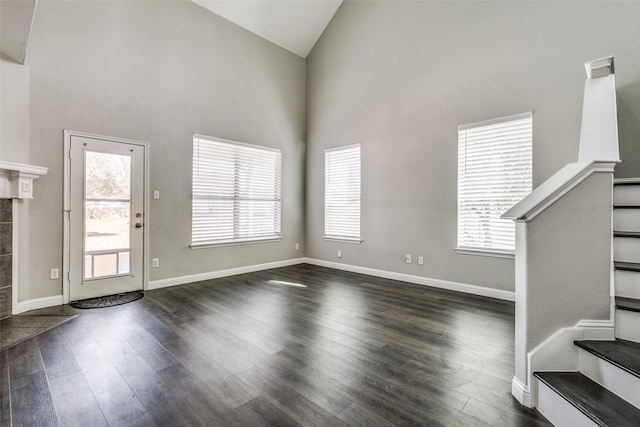 foyer entrance featuring baseboards, stairs, high vaulted ceiling, and dark wood-type flooring