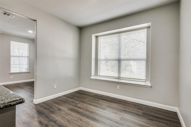 unfurnished room featuring dark wood-style floors, visible vents, and baseboards