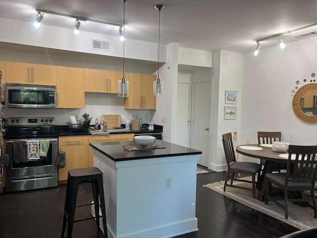 kitchen with visible vents, dark countertops, a kitchen island, appliances with stainless steel finishes, and light brown cabinets