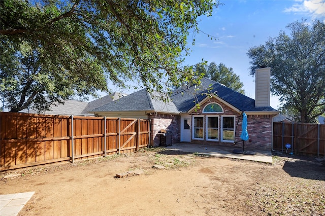 back of property with a patio, a fenced backyard, brick siding, a shingled roof, and a chimney