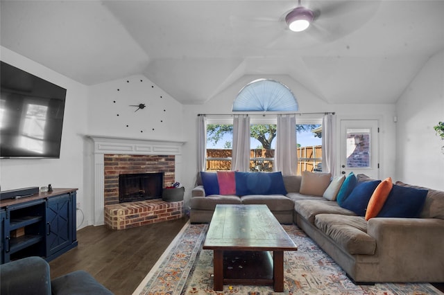 living room featuring lofted ceiling, dark wood-style floors, and a brick fireplace