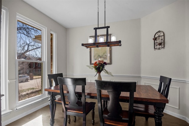 dining room with a wealth of natural light, a wainscoted wall, and an inviting chandelier