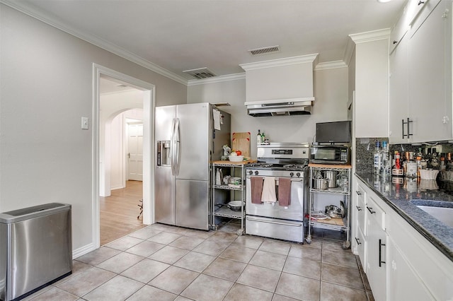 kitchen featuring arched walkways, stainless steel appliances, light tile patterned flooring, and visible vents