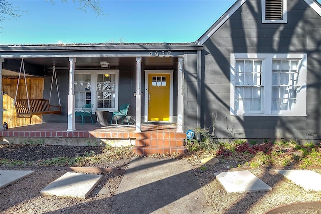 view of exterior entry with covered porch and visible vents