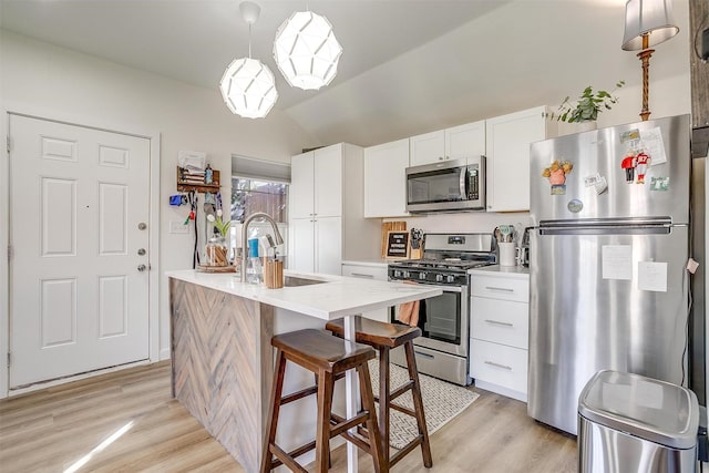 kitchen with lofted ceiling, stainless steel appliances, a sink, white cabinets, and light wood-type flooring