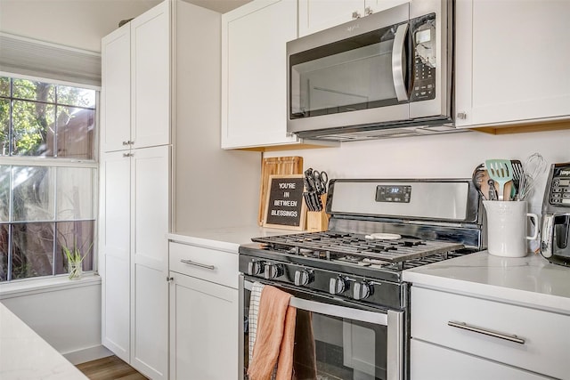 kitchen featuring white cabinetry, stainless steel appliances, and light stone counters