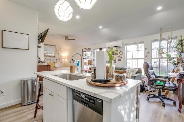 kitchen with a sink, white cabinetry, open floor plan, stainless steel dishwasher, and a wall mounted air conditioner