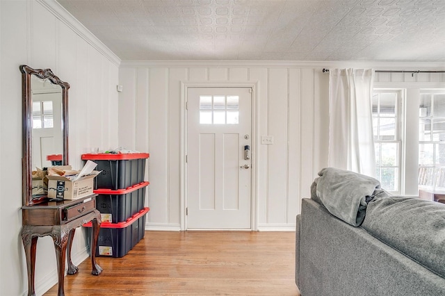 entryway with wood finished floors and crown molding