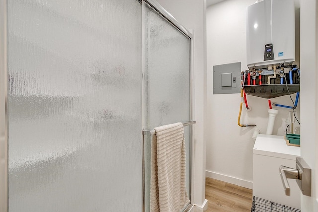 full bath featuring electric panel, baseboards, wood finished floors, tankless water heater, and a shower stall