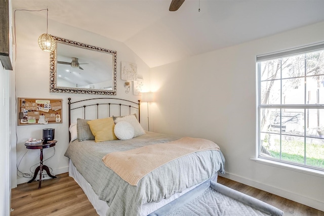 bedroom featuring a ceiling fan, vaulted ceiling, baseboards, and wood finished floors