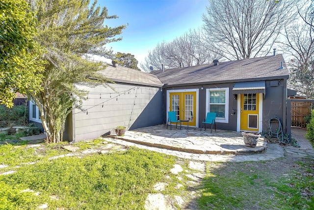 rear view of property featuring french doors, a patio area, fence, and concrete block siding