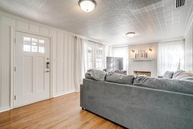 living room featuring an ornate ceiling, a wealth of natural light, visible vents, and light wood-style flooring