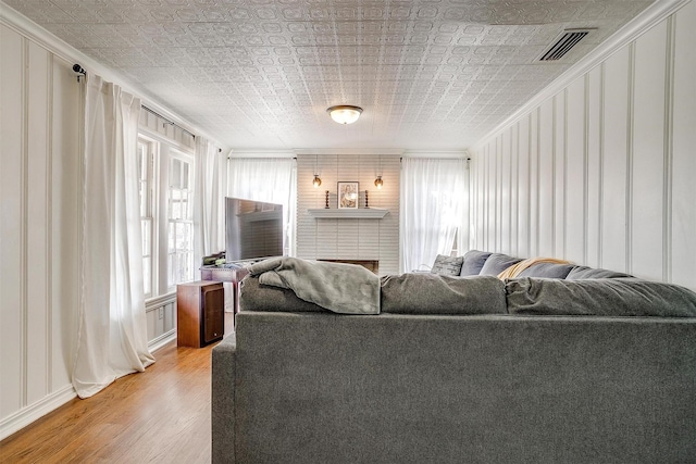 living room with plenty of natural light, light wood-type flooring, an ornate ceiling, and visible vents