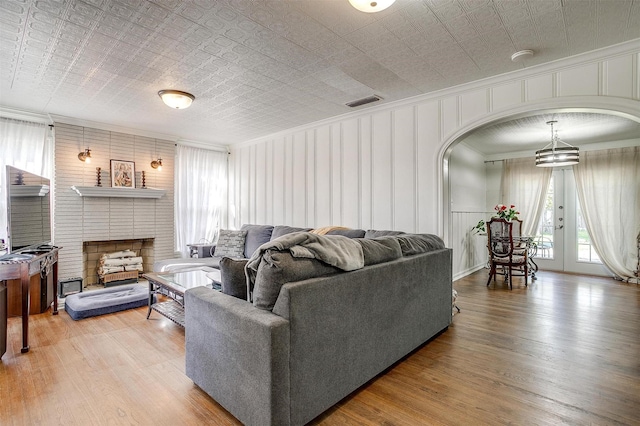 living room with arched walkways, visible vents, light wood-type flooring, and an ornate ceiling