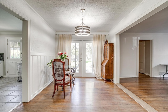 living area featuring ornamental molding, french doors, wood finished floors, and an ornate ceiling