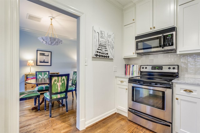 kitchen featuring ornamental molding, appliances with stainless steel finishes, visible vents, and decorative backsplash