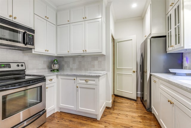 kitchen featuring tasteful backsplash, white cabinetry, stainless steel appliances, and crown molding